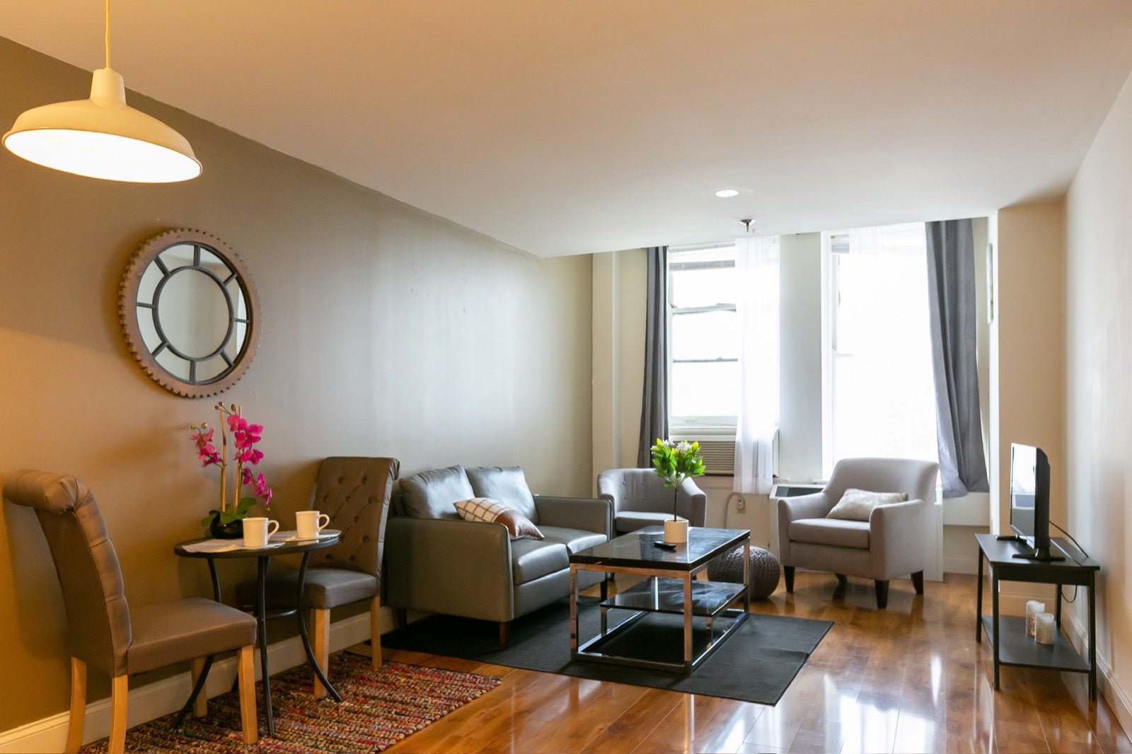 Furnished apartment living room with gray sofa and industrial gear mirror, Exchange Building Memphis