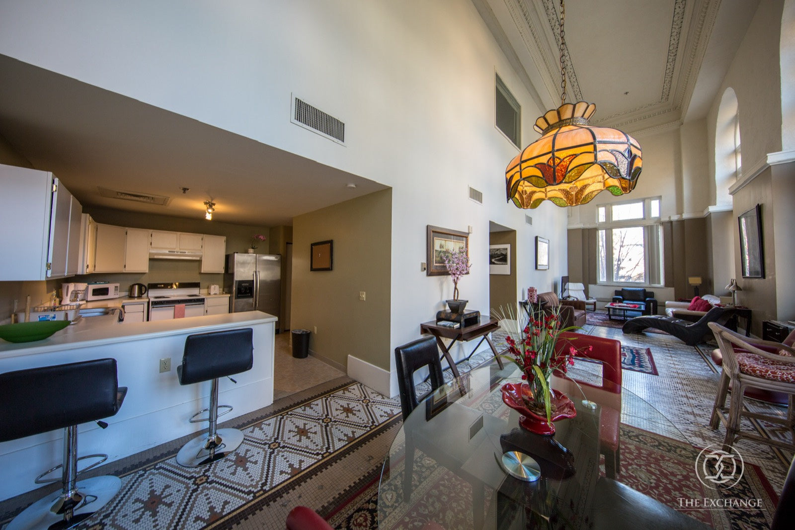 Furnished high-ceiling loft with stained-glass pendant and open kitchen, Exchange Building Memphis